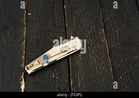 Knife with a metal handle in the folded form. Wooden black background Stock Photo