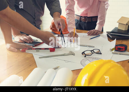 Engineer and Architect concept, Engineer Architects office team working and discussing house plan with blueprints and house model, Vintage Effect Stock Photo