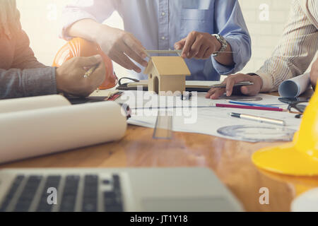 Engineer and Architect concept, Engineer Architects office team working and discussing house plan with blueprints and house model, Vintage Effect Stock Photo