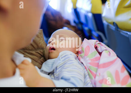 Adorable Baby Sleeping On Airplane ,Toddler boy sleeping on father's laps while traveling in airplane,Flying with children. Dad and sleeping 10 months Stock Photo