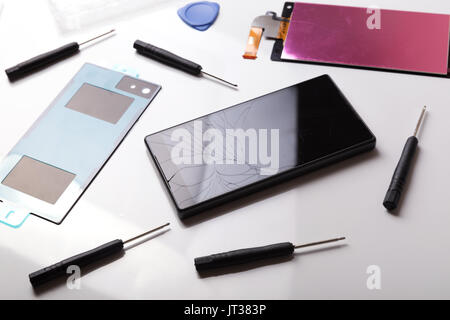 smartphone repair service. phone with broken display and spare parts on the table Stock Photo