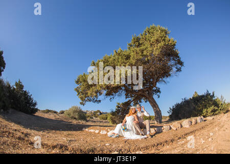 Newlywed couple sitting under a tree in summer Stock Photo