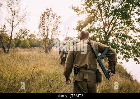 Group Of Reenactors Men Dressed As Russian Soviet Red Army Infantry Soldiers Of World War II Marching In Autumn Field With Weapons At Historical Reena Stock Photo