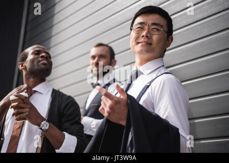 young stylish multiethnic businessmen in formalwear standing outdoors, business team meeting Stock Photo