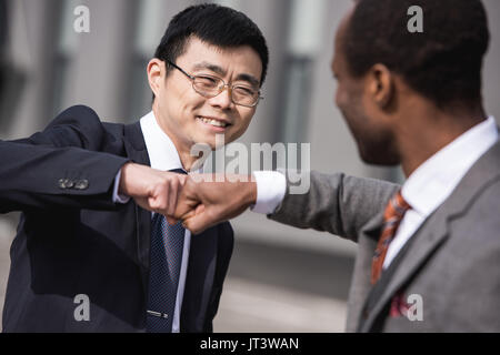 young smiling multiethnic businessmen in formalwear celebrating success, business team meeting Stock Photo