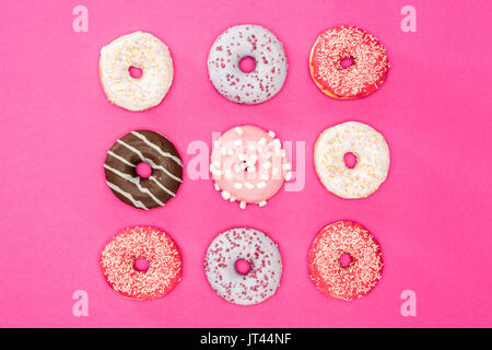 Overhead view of sweet donuts with colorful glaze on pink surface. donuts chocolate background  Stock Photo