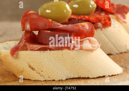 selection of spanish meat with olives on sliced crusty bread Stock Photo