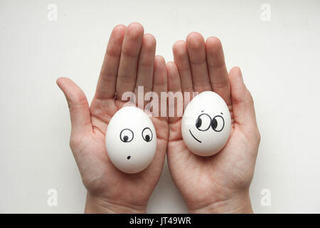 Diet concept. Female hands holding eggs with funny little faces painted. Photo for your design Stock Photo