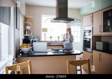 Woman in her kitchen with a cup of tea. She is having some time to herself. Stock Photo