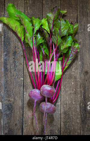 Bunch of Baby Beets with foliage, on wooden background. selective focus Stock Photo