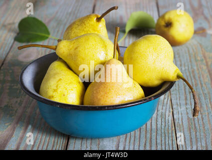 yellow pear in a metal bowl on a wooden table Stock Photo