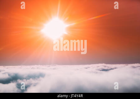 Sun shining in Sunny Clear Sky Over White Fluffy Clouds From Height Flight Of Plane. Bright Yellow And Orange Colors Of Sunny Sky. Stock Photo