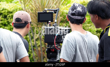 Behind the scenes of movie shooting or video production and film crew team with camera equipment at outdoor location. Stock Photo