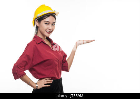 Asian woman engineer in red shirt and yellow safety cap smiling while showing palm hand. People gesturing in business and enginerring concept Stock Photo
