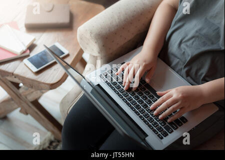 Woman typing on laptop computer keyboard while using internet for online activity. Wireless working and internet of things concept Stock Photo