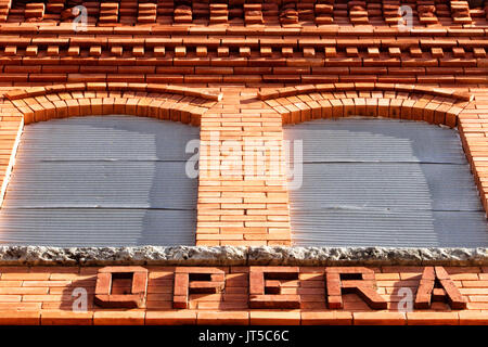 A detail view of a brick Opera House building showing two windows and the word 'Opera.' Stock Photo