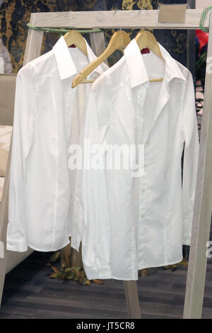Ironed male clothes white shirts on wooden hangers Stock Photo