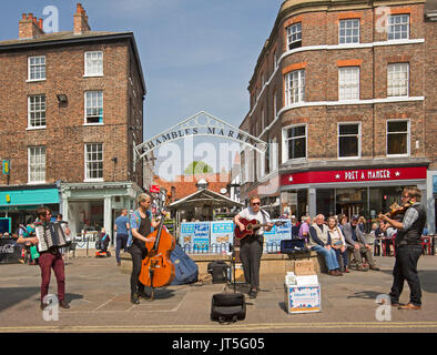 Group of musicians, The Hyde Family, busking beside entrance to The Shambles with shoppers enjoying the free performance in city of York, England, Stock Photo