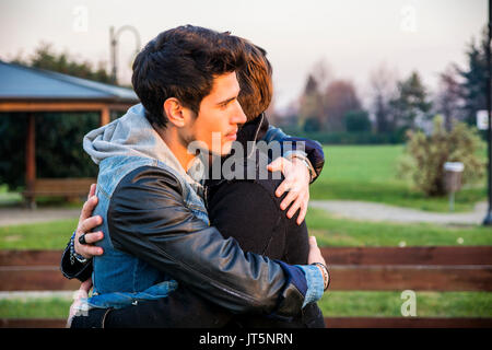 Portrait of cheerful and handsome man hugging his best friend and looking away outdoor Stock Photo