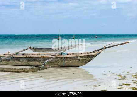 Traditional dhow fishing boats by shoreline and in ocean, Diani beach, Kenya Stock Photo