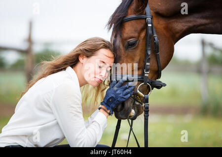 Young happy horsewoman in white shirt with her bay stallion Stock Photo