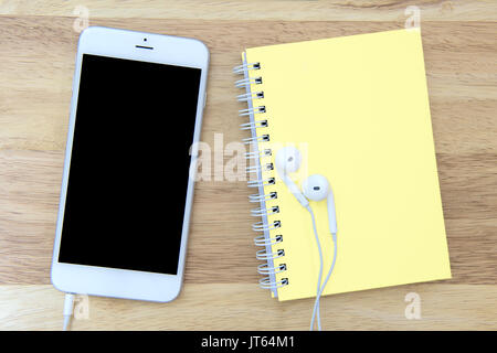 Phone and notebook with blank screen on wooden background. Stock Photo