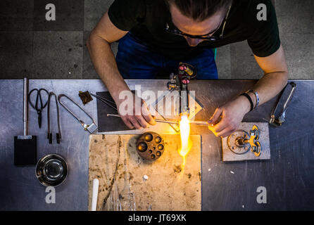 Top View of Glassblowing Professional Working on a Torch Flame with Glass Tubes (focus on the tools) Stock Photo