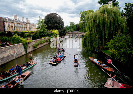 Tourists enjoying a punt along the River Cam passing under historic stone bridges and besides famous colleges of Cambridge University in England.