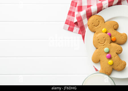 Sweet gingerbread men and glass of milk. Xmas gingerbread on white table. Stock Photo