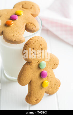 Sweet gingerbread men and glass of milk. Xmas gingerbread on white table. Stock Photo