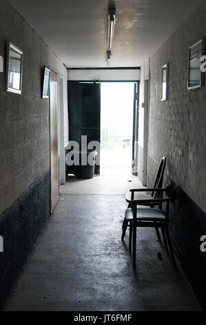 England, Hallway, Passageway, Light Coming From the Doorway, Dark Corridor with Light at the End, 2 Empty Wooden Chairs, Inside to Outside, Interior Stock Photo