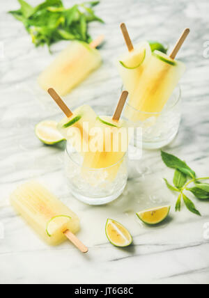 Summer refreshing lemonade popsicles with lime and mint in glasses with chipped ice, selective focus Stock Photo