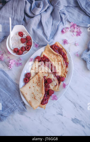 Crepes with raspberry chia jam served on a white plate Stock Photo