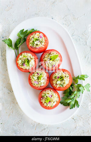 Quinoa Tabbouleh stuffed Tomatoes. Photographed on a white plaster background. Stock Photo