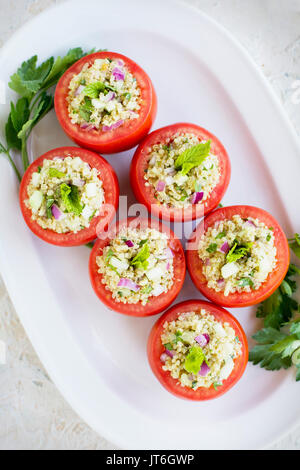 Quinoa Tabbouleh stuffed Tomatoes. Photographed on a white plaster background. Stock Photo