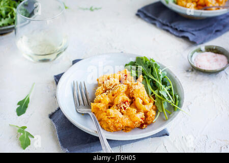 Manchego Piquillo Pepper Mac n Cheese topped with Marcona Almonds. Served with arugula and white wine. Photographed on a white plaster background. Stock Photo