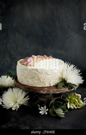 Marzipan Almond Cake with a Orange Blossom Mascarpone Frosting on a wooden pedestal, served with Rosé wine.  Photographed on a black/gray background. Stock Photo