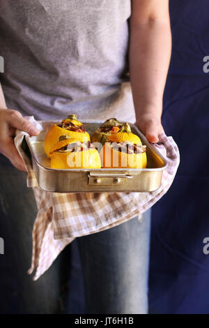 Female hands holding a pan with roasted stuffed zucchini Stock Photo