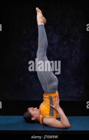 Woman doingh Ashtanga Vinyasa Yoga inverted asana Salamba sarvan Stock Photo