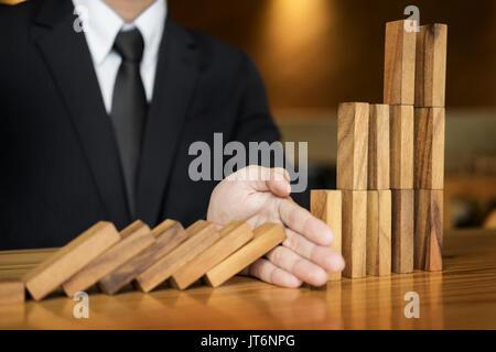 businessman hand stop dominoes continuous toppled or risk with copyspace Stock Photo