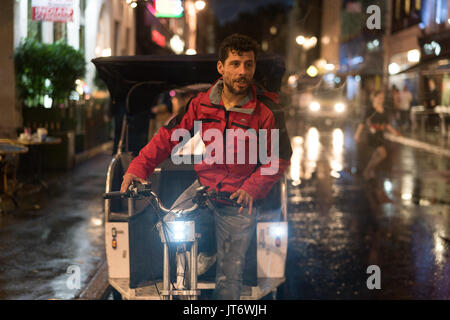 A view of a cycle tuktuk rider on the streets of Soho in London on a rainy night. From a series of photos taken on a rainy night in Soho, London. Phot Stock Photo