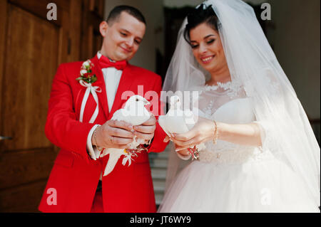 Gorgeous wedding couple releasing wedding white doves into the air. Stock Photo