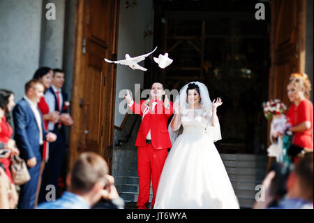 Gorgeous wedding couple releasing wedding white doves into the air. Stock Photo