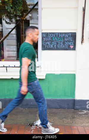 Brighton, UK. A man walks past an anti-racism sign on a pub in the Lanes at Brighton. Stock Photo