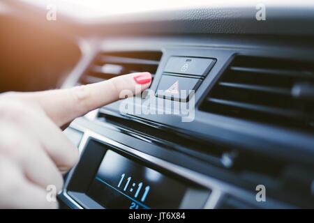 Woman turns on the emergency lights in the car. Modern car interior Stock Photo