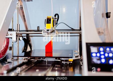 3d printer working and printing red plastic component Stock Photo