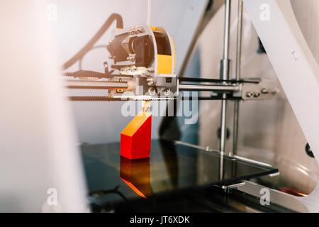 3d printer working and printing red plastic component Stock Photo