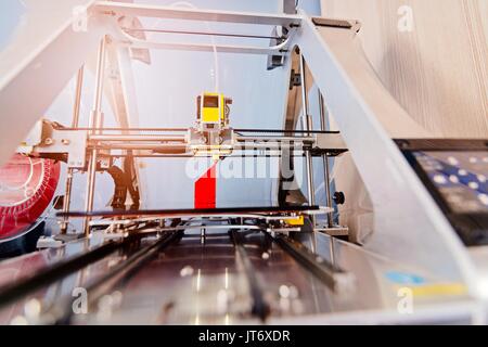 3d printer working and printing red plastic component Stock Photo