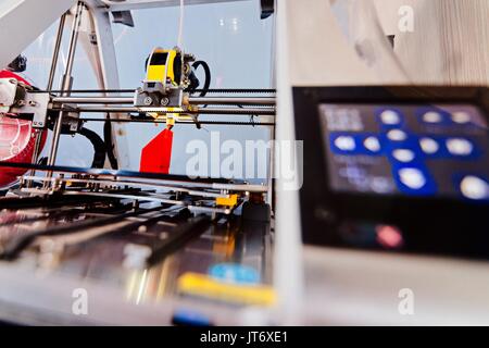3d printer working and printing red plastic component Stock Photo