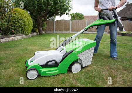 A casually dressed woman mowing the lawn with a VIKING MA339C cordless lawnmower. Candid. Summer, UK. Stock Photo